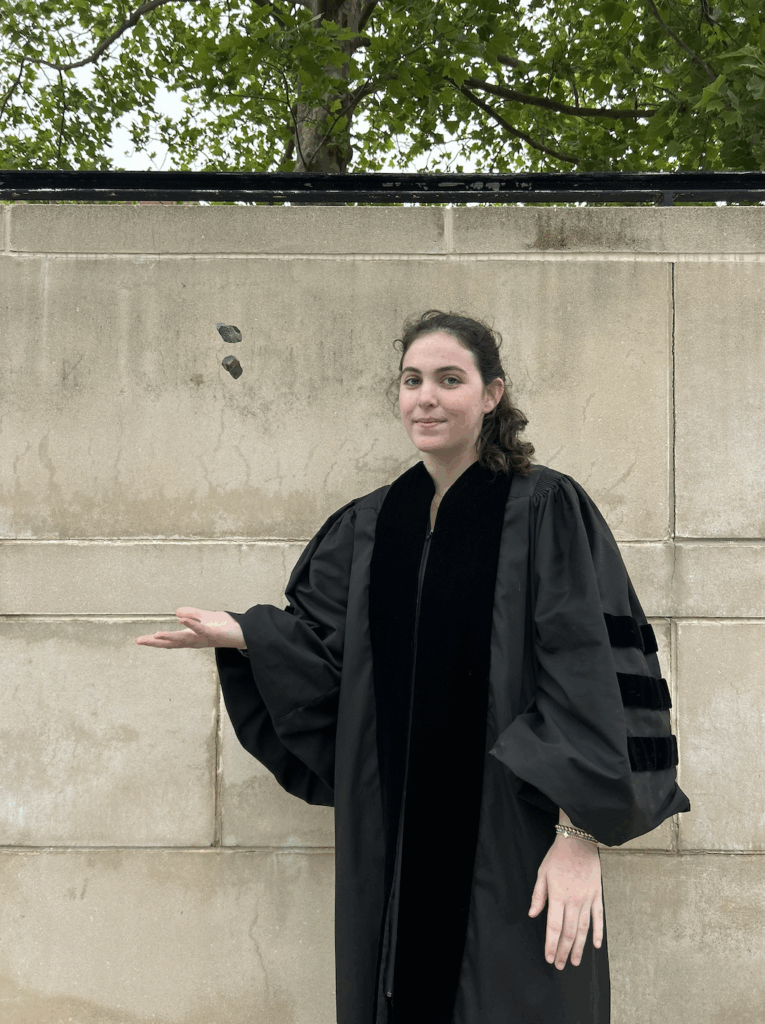 Woman in robe levitating two rocks outside.